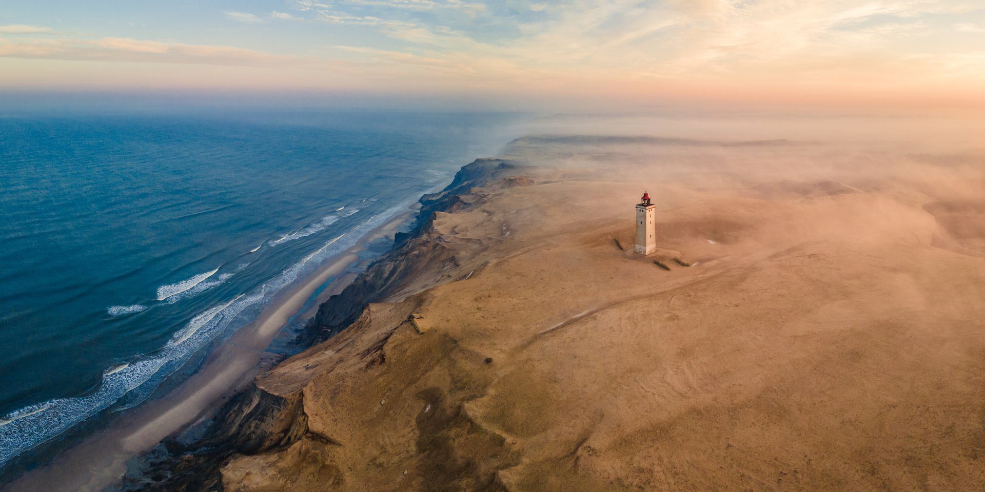 The iconic Rubjerg Knude Lighthouse on a cliff, representing a significant natural landmark and attraction in the Nordjütland region near Saltum.