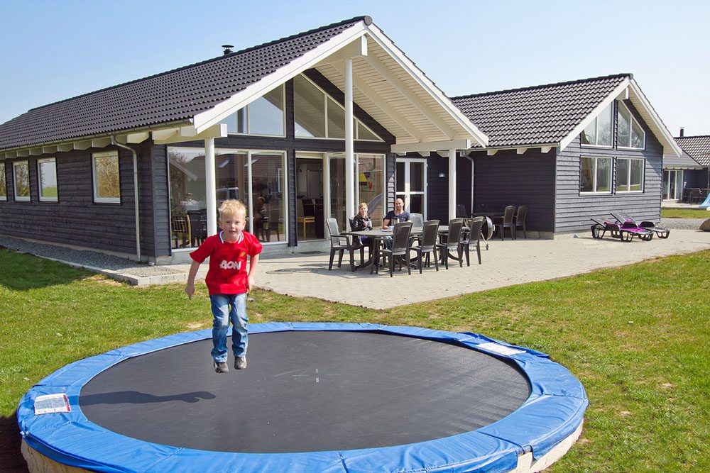 Junge beim Trampoline springen im Ferienhaus in Dänemark