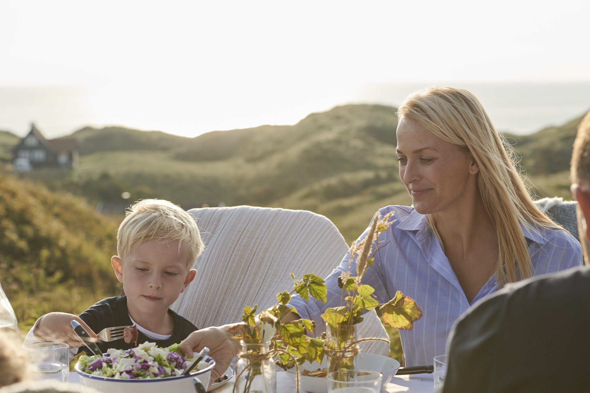 Eine glückliche Familie sitzt draußen beim Ferienhaus in Dänemark im Frühling